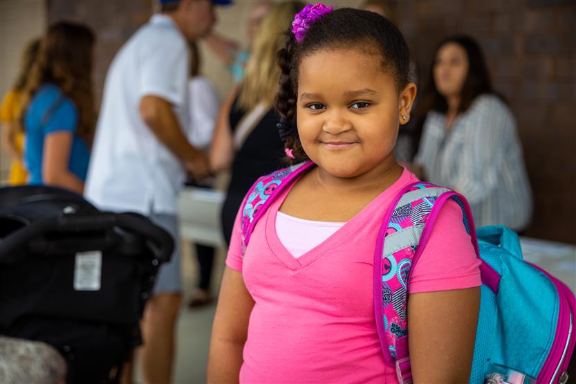 A girl wearing a pink shirt smiles